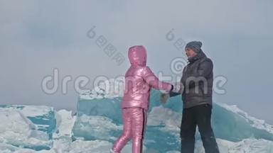 在冰封的湖面上，年轻夫妇在冬天散步时玩得很开心。 情侣们玩得很开心，笑了